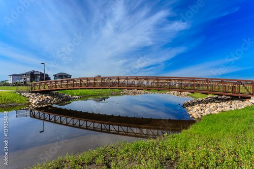 Fototapeta Naklejka Na Ścianę i Meble -  A bridge spans a body of water, with a reflection of the bridge in the water