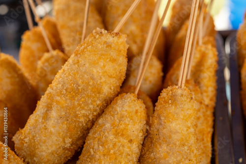 Close-up of crispy golden corn dogs skewered on sticks, a popular street food snack with crunchy breading texture. Perfect for culinary concepts, fast food visuals, and street food themes. photo