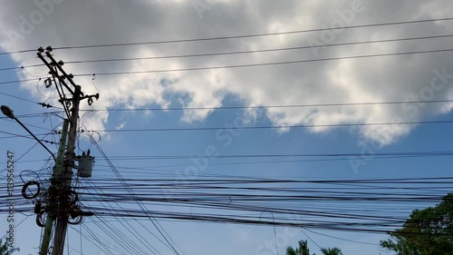 Tangled Power Lines Against a Cloudy Blue Sky