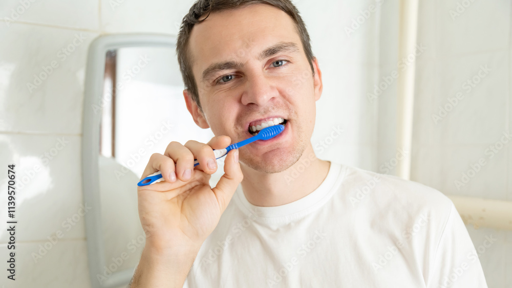 Young man brushing teeth with toothbrush at home in the bathroom Young man brushing teeth with toothbrush at home in the bathroom