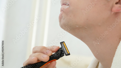 Handsome man shaving in the bathroom.