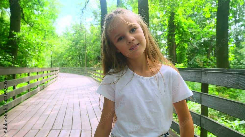Close-up portrait of a child showing a robot in slow motion of a green forest. Happy girl walking on a wooden bridge in a nature park on summer vacation Close-up portrait of a child showing a robot in slow motion of a green forest. Happy girl walking on a wooden bridge in a nature park on summer vacation