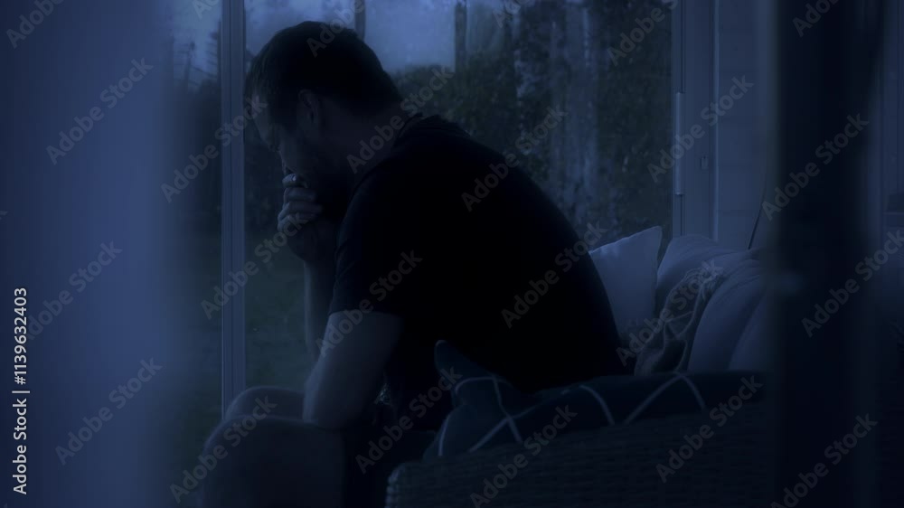 Man sitting by a window at night in deep thought with dim lighting and a calm atmosphere Man sitting by a window at night in deep thought with dim lighting and a calm atmosphere