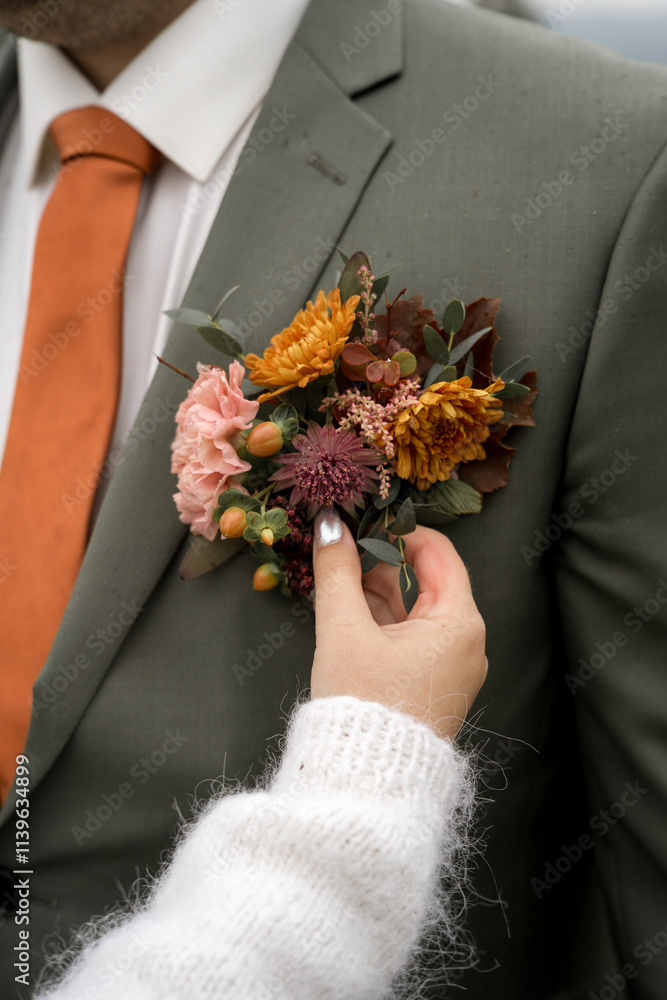 Bride adjusting boutonniere on groom's jacket Bride adjusting boutonniere on groom's jacket
