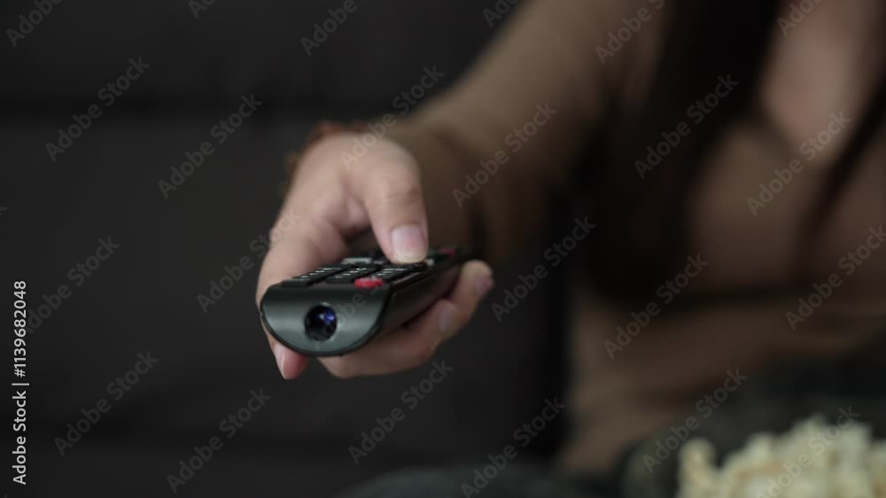 Woman Watching smart TV and using remote controller Hand holding popcorn at home Woman Watching smart TV and using remote controller Hand holding popcorn at home