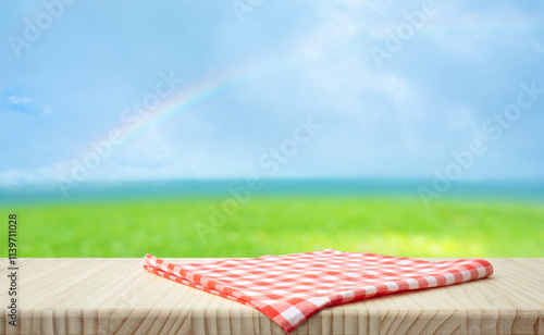 Fabric cloth or placemat on wood table top on fresh blue sky with rainbow