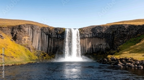 Majestic Waterfall Cascading Over Unique Rock Formations Under Clear Blue Sky