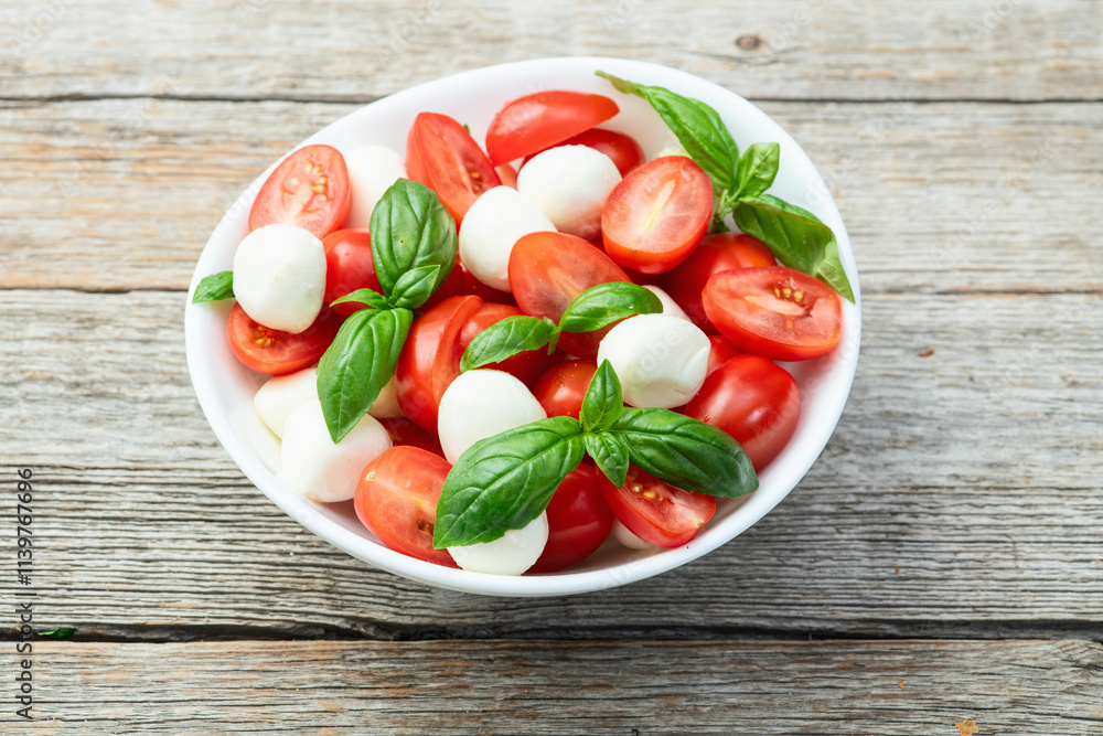 Basil leaves , cherry tomatoes and mozzarella cheese . In bowl food photography Basil leaves , cherry tomatoes and mozzarella cheese . In bowl food photography