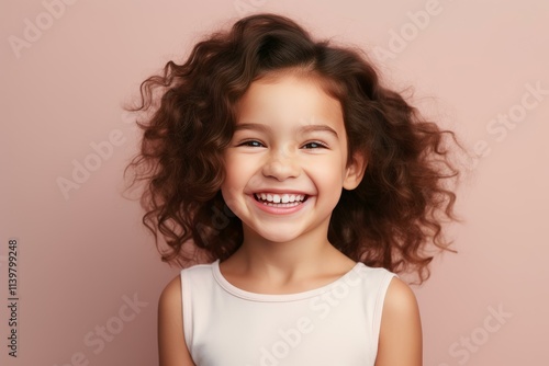 Studio portrait of cheerful young girl with voluminous curly brown hair, expressing happiness and joy