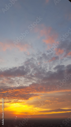 With the setting sun, the sky bursts into vibrant tones of amber and scarlet, adorned with expansive clouds, forming a mesmerizing scene with an intense fiery hue.