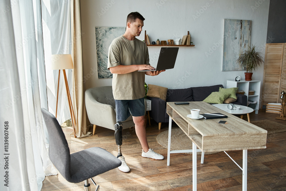 Handsome young man stands at a desk using a laptop in a stylish living room. Handsome young man stands at a desk using a laptop in a stylish living room.