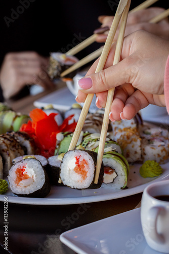 Hand Holding a Piece of Sushi and Lifting It from a Plate