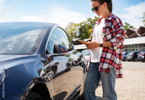 Bilde på lerret Woman unlocking car-sharing auto remotely with mobile app and smartphone on city street