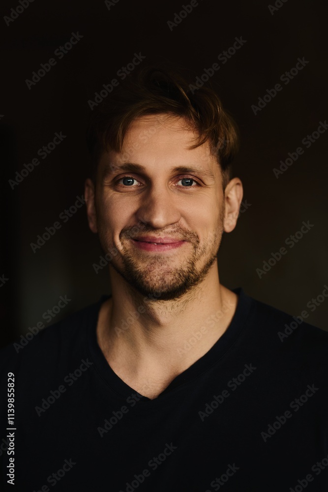 Close-up portrait of handsome young Caucasian man smiling against apartment background Close-up portrait of handsome young Caucasian man smiling against apartment background