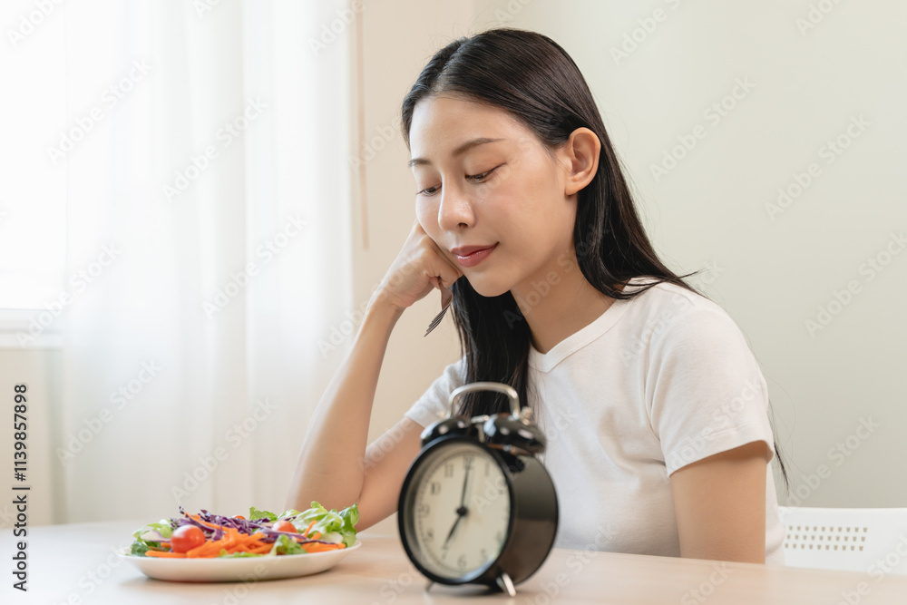 Intermittent fasting with clock, close up young woman, girl diet, waiting time to eat ketogenic low carb, green vegetable salad on plate. Eat food healthy first meal on brunch, lunch on table at home. Intermittent fasting with clock, close up young woman, girl diet, waiting time to eat ketogenic low carb, green vegetable salad on plate. Eat food healthy first meal on brunch, lunch on table at home.