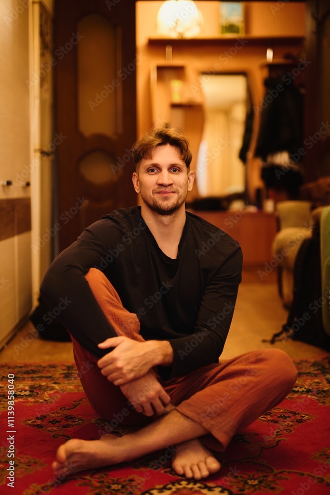 Portrait of young Caucasian man, hipster yogi against the background of retro apartment with carpets Portrait of young Caucasian man, hipster yogi against the background of retro apartment with carpets