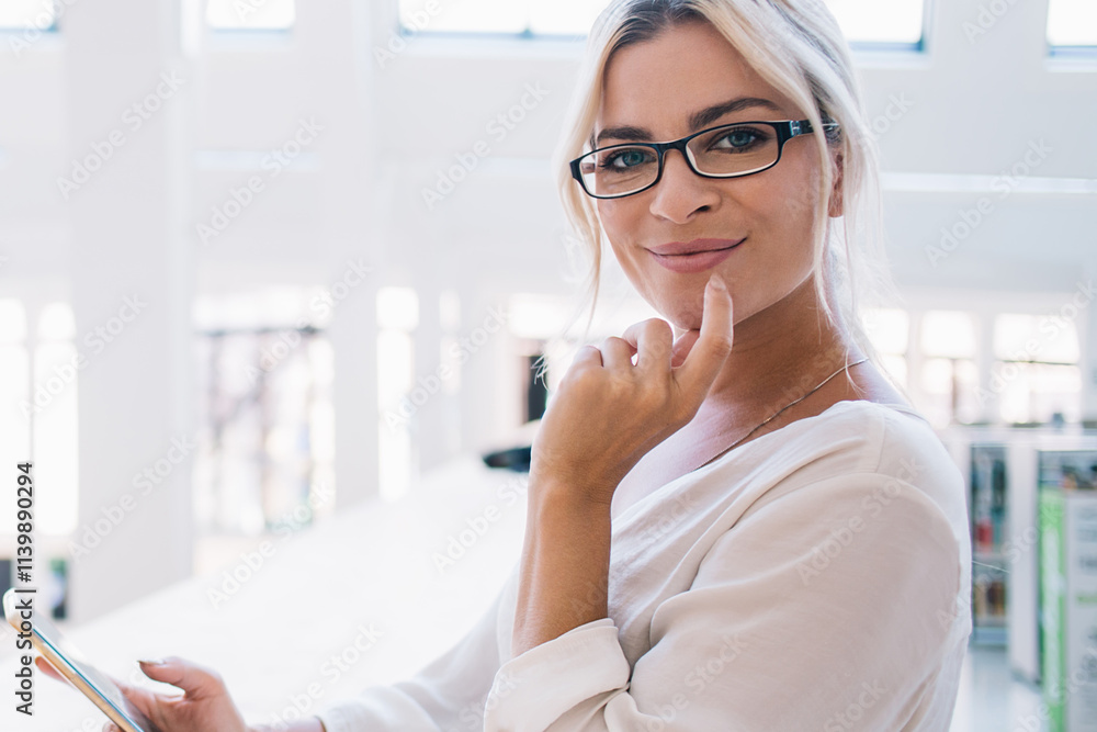 Positive businesswoman with smartphone and book looking at camera Positive businesswoman with smartphone and book looking at camera
