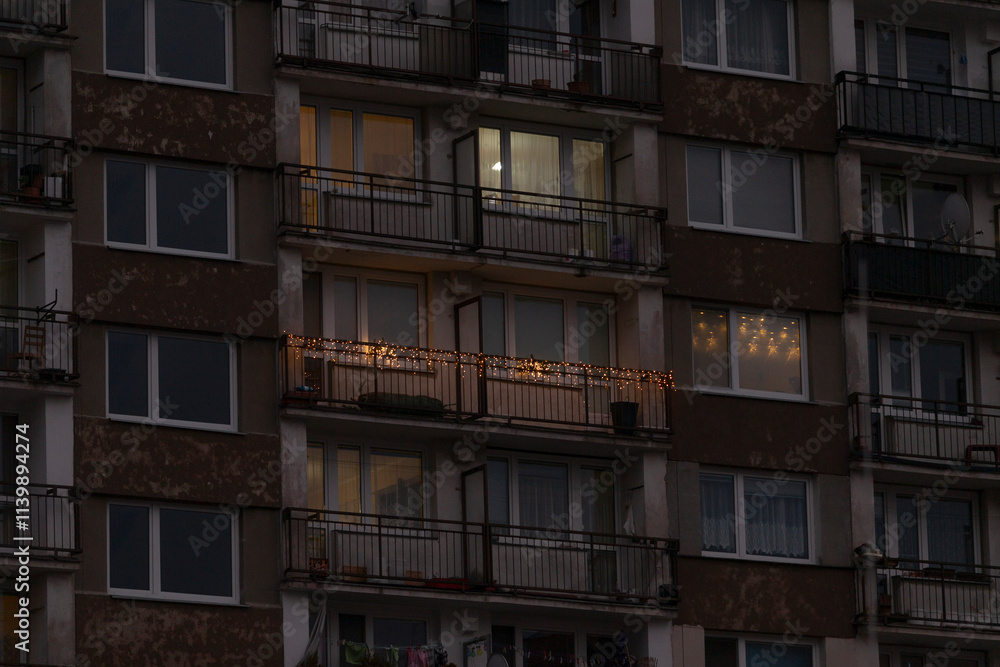 Fototapeta premium A tall building that features numerous windows and balconies, beautifully illuminated at night, creating a stunning architectural view