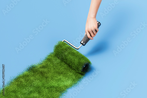 Hand painting green grass with paint roller on blue background