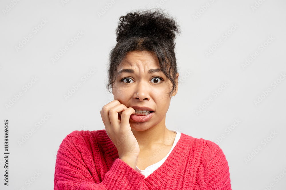 Scared young woman biting her nails on white background