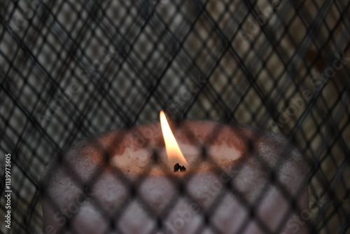 Vela encendida a traves de una reja