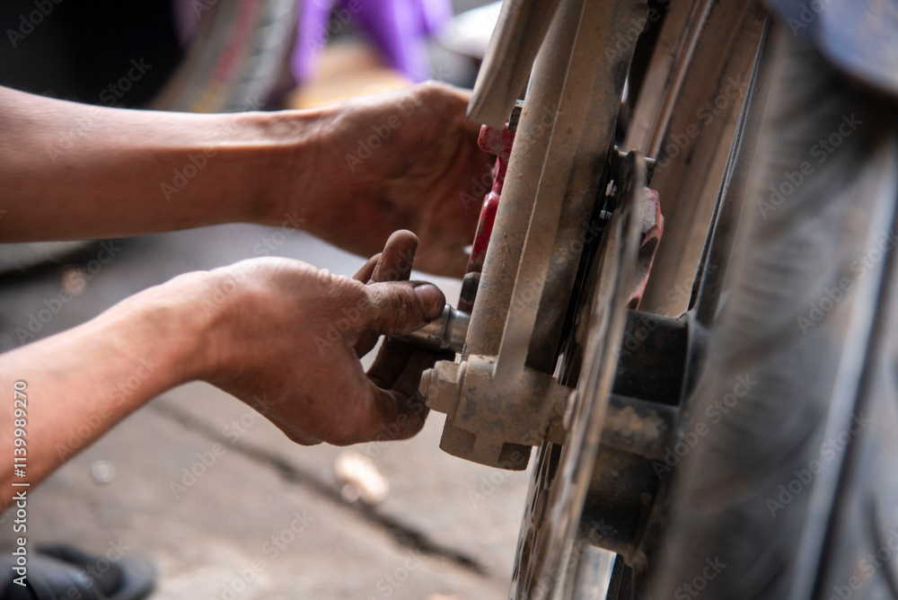 Mechanic sitting focused using wrench to repair motorcycle brake, drum brake pads at repair shop Mechanic sitting focused using wrench to repair motorcycle brake, drum brake pads at repair shop