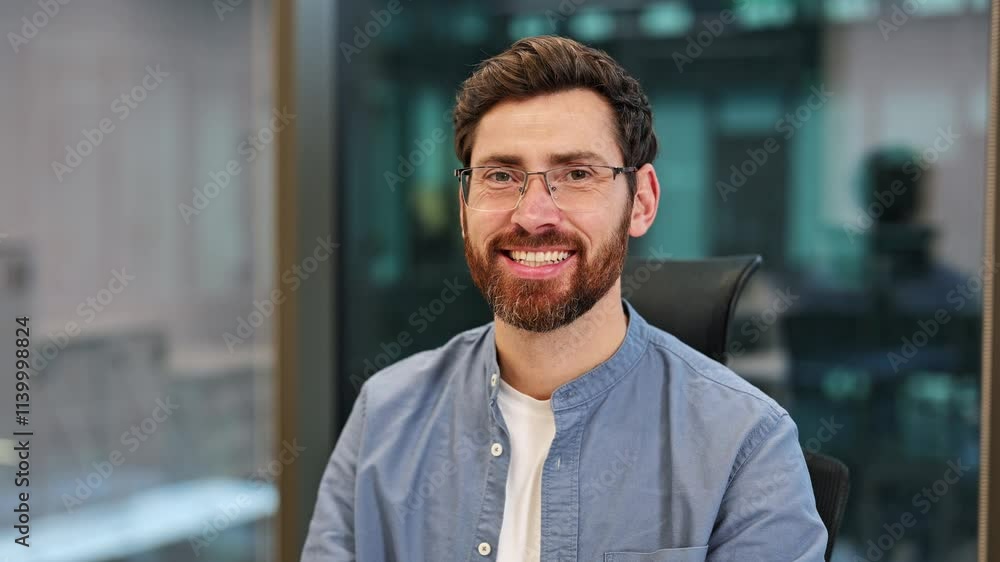 Portrait of triumphant businessman in glasses smiling at the office. Professional male dressed casually feeling joy and happiness. Positive male expressing satisfaction looking at camera with smile. Portrait of triumphant businessman in glasses smiling at the office. Professional male dressed casually feeling joy and happiness. Positive male expressing satisfaction looking at camera with smile.