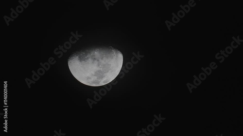 Timelapse of the waxing moon as it is moving acroww the sky, with clouds obstructing it ocassionally. photo