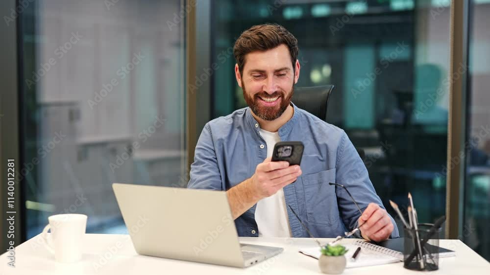 Thriving businessman using phone in office. Professional manager working at modern workplace. Stylish guy in casual shirt feels happy. Strong businessman IT specialist using phone in office Thriving businessman using phone in office. Professional manager working at modern workplace. Stylish guy in casual shirt feels happy. Strong businessman IT specialist using phone in office