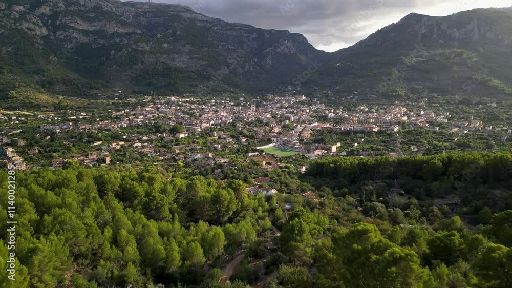 Picturesque aerial view of Soller, a charming town in Mallorca, nestled between lush greenery and dramatic mountain ranges at sunset Picturesque aerial view of Soller, a charming town in Mallorca, nestled between lush greenery and dramatic mountain ranges at sunset