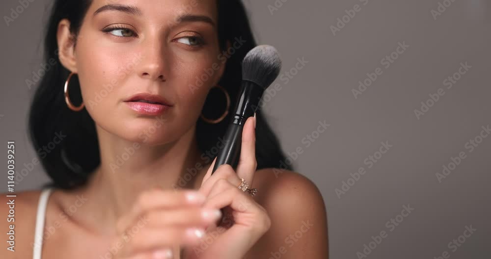 Close-up of a brunette woman with glowing skin and natural makeup, holding a makeup brush gracefully. Perfect for beauty, skincare, or cosmetics branding and promotions. Close-up of a brunette woman with glowing skin and natural makeup, holding a makeup brush gracefully. Perfect for beauty, skincare, or cosmetics branding and promotions.