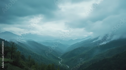Majestic mountain landscape featuring cloudy skies and a serene stream flowing through the lush green valley in a misty atmosphere.