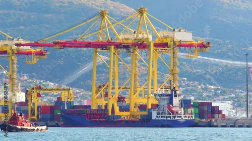 Working crane bridge lifting container cargo to freight ship at shipyard in morning. Transportation and Logistics in the city. 