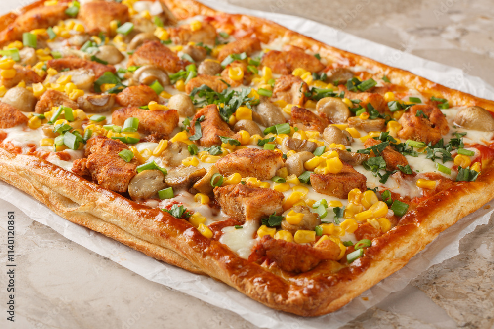 Rectangular puff pizza pie with spicy chicken, mushrooms, corn, mozzarella cheese and tomato sauce close-up on parchment paper on table. Horizontal
