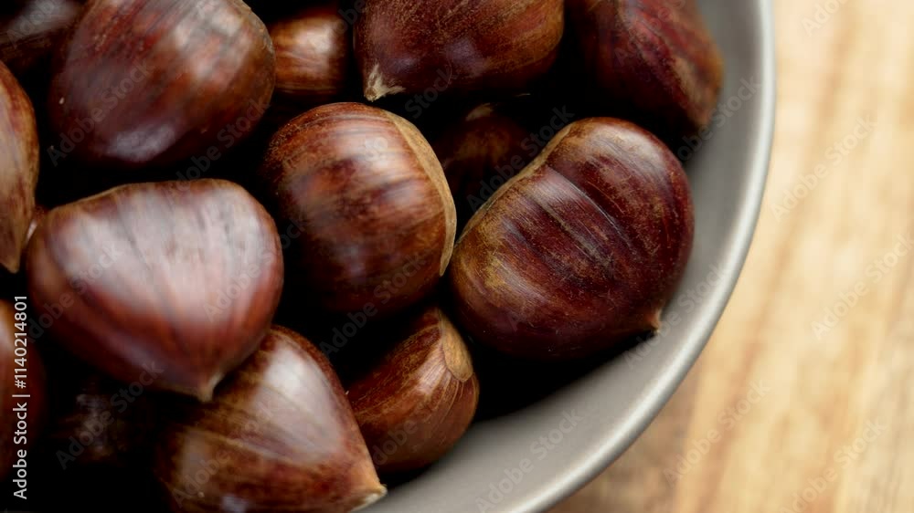 Fresh organic chestnuts with smooth brown shells in ceramic bowl. Close-up view on a wooden background Fresh organic chestnuts with smooth brown shells in ceramic bowl. Close-up view on a wooden background