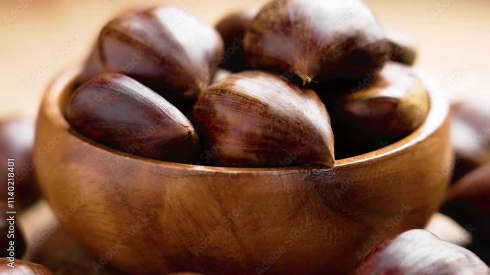 Rustic organic whole chestnuts filled wooden bowl and scattered on brown board. Close-up. Front view. Rotation Rustic organic whole chestnuts filled wooden bowl and scattered on brown board. Close-up. Front view. Rotation