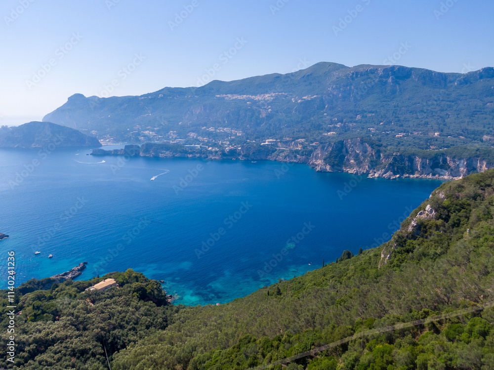 Aerial view of coastline, turquoise water, and forested slopes. Aerial view of coastline, turquoise water, and forested slopes.