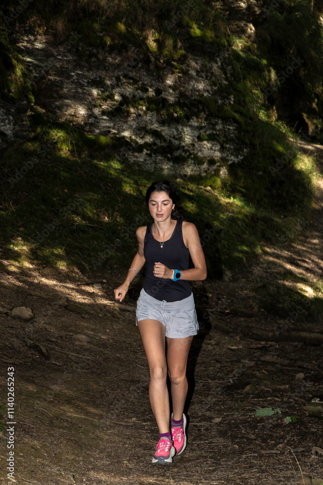 Young woman running on a forest trail with sunlight filtering through the trees, surrounded by lush greenery. Young woman running on a forest trail with sunlight filtering through the trees, surrounded by lush greenery.