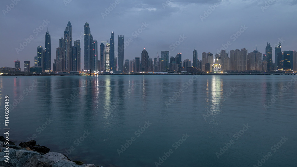 Fototapeta premium Panorama of modern skyscrapers in Dubai city night to day timelapse from the Palm Jumeirah Island.