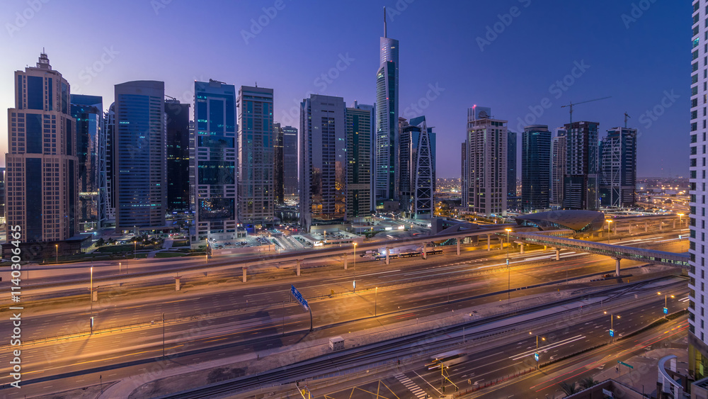 Fototapeta premium Aerial view of Jumeirah lakes towers skyscrapers night to day timelapse with traffic on sheikh zayed road.