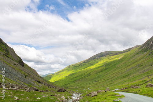 Descend of the B5289 road with steep grade from Honister Pass in the Lake District, Cumbria, UK surrounded by green mountains with pasture photo