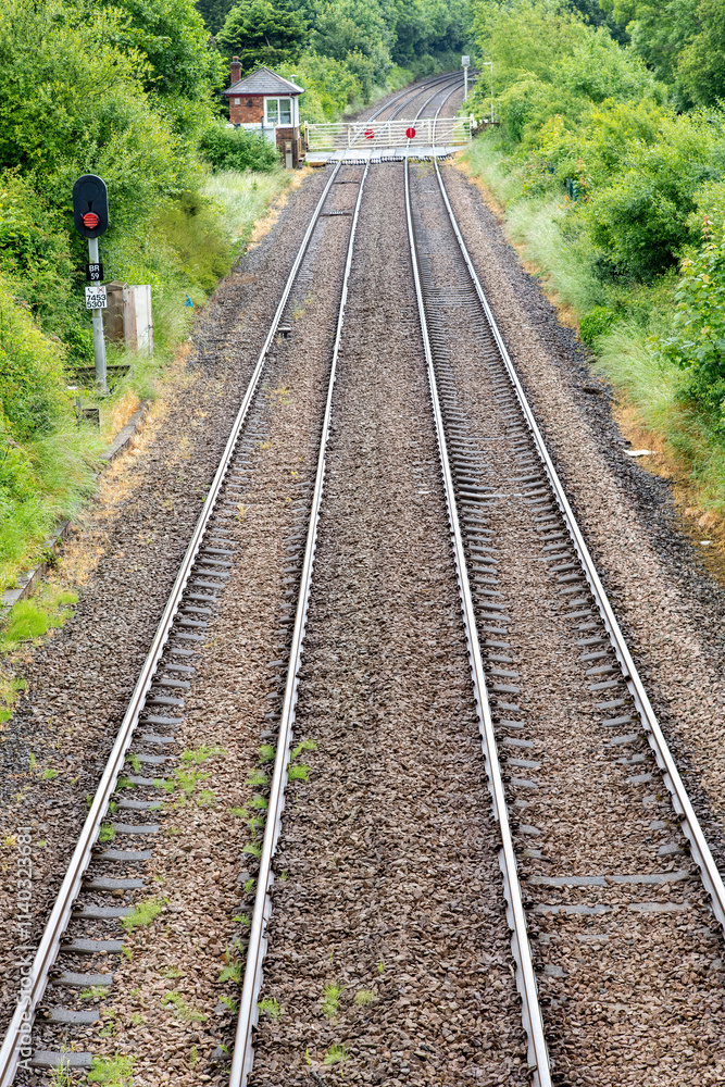 High level vertical view of train tracks diappearing around bend in distance and fence over tracks just outside station of Llanfairpwllgwyngyll, UK High level vertical view of train tracks diappearing around bend in distance and fence over tracks just outside station of Llanfairpwllgwyngyll, UK