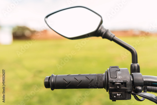 Black motorcycle rearview mirror and motorcycle handlebar on a sunny day of travel