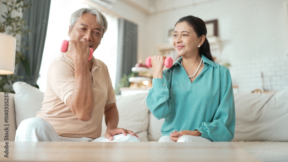Happy elderly couple exercising together with dumbbells at home, focusing on muscle strength, joint health, and physical wellness for improved mobility and healthy aging. Retirement concept. Myrmidon. Happy elderly couple exercising together with dumbbells at home, focusing on muscle strength, joint health, and physical wellness for improved mobility and healthy aging. Retirement concept. Myrmidon.