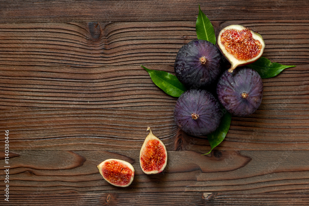 Whole and cut fresh figs with green leaves on wooden table. Top view Whole and cut fresh figs with green leaves on wooden table. Top view