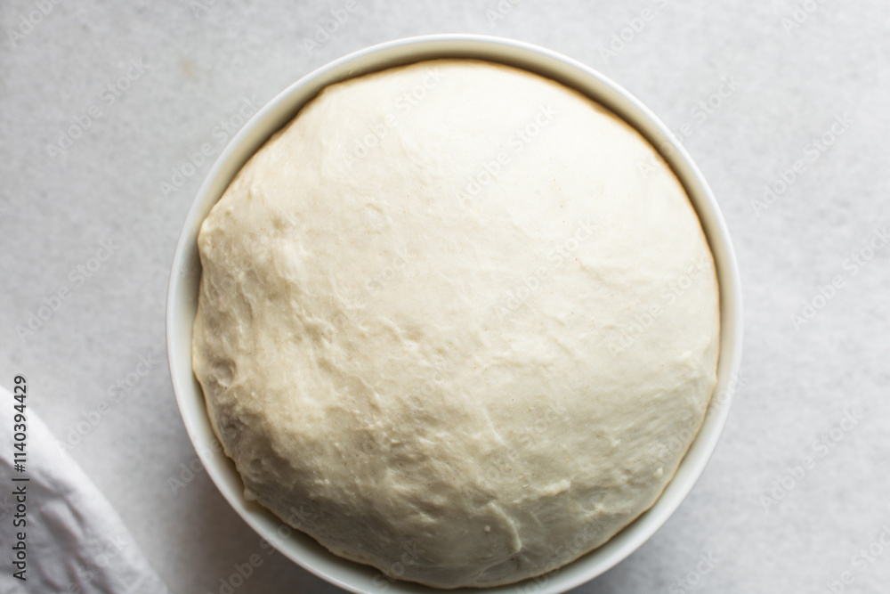 Bread dough that has doubled in size, dough that has risen, proofed dough in a white bowl Bread dough that has doubled in size, dough that has risen, proofed dough in a white bowl