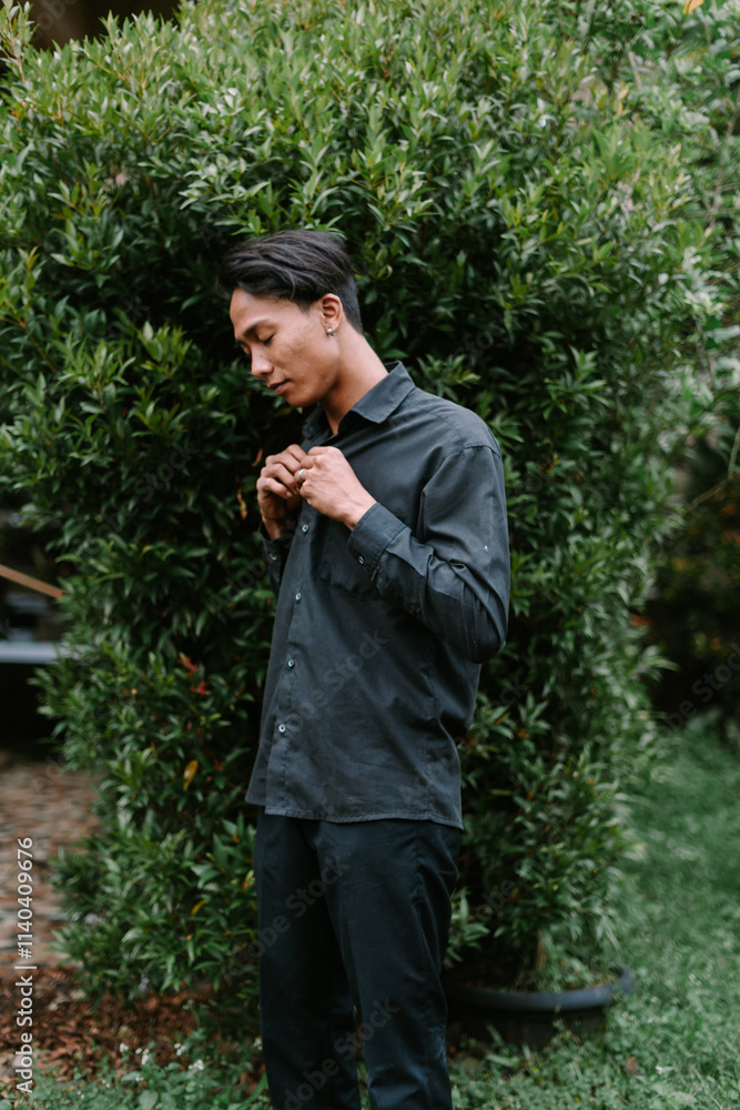 A Southeast Asian man adjusting his shirt buttons A Southeast Asian man adjusting his shirt buttons