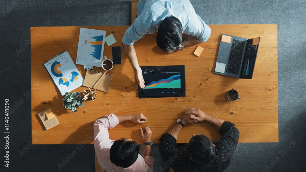 © Summit Art Creations - Top aerial view of business man present financial graph to group of smart investors. Professional male leader analyze graph and explain marketing idea by using tablet on meeting table. Convocation.