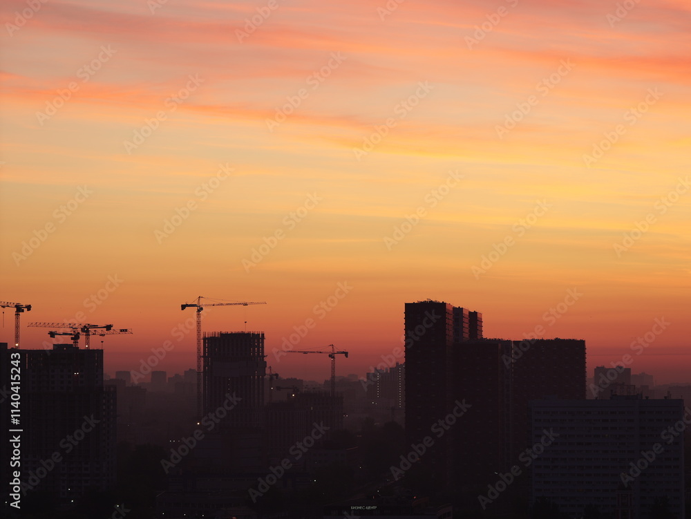 Construction cranes against the backdrop of a vibrant city sunrise, with the warm light illuminating the skyline. Perfect for industrial, urban, and morning photography Construction cranes against the backdrop of a vibrant city sunrise, with the warm light illuminating the skyline. Perfect for industrial, urban, and morning photography