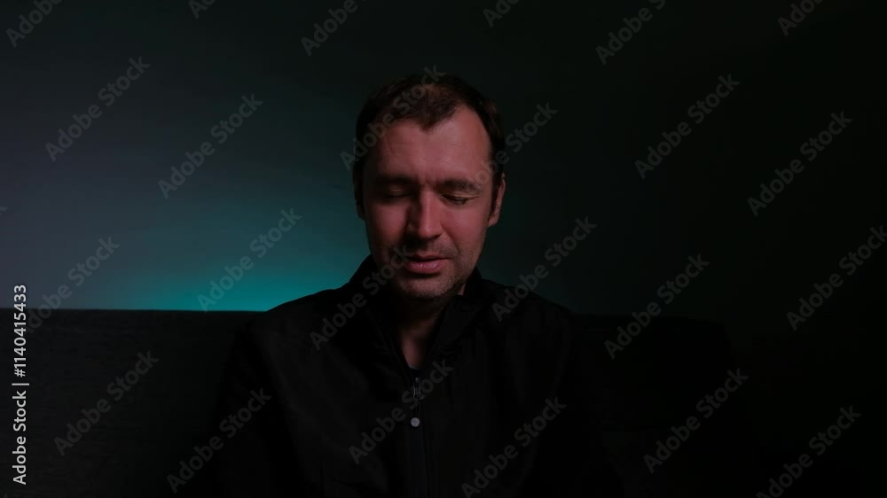 A man is crying and covering his face with his hands. Portrait on a dark background. A man is crying and covering his face with his hands. Portrait on a dark background.